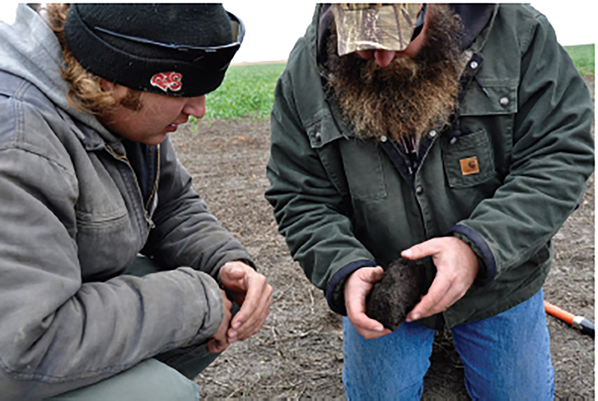 Producer Tony Wagnerand and Lee Briese, Certified Crop Adviser and Society member (right), look at soil quality. Photo by Abbey Wick.